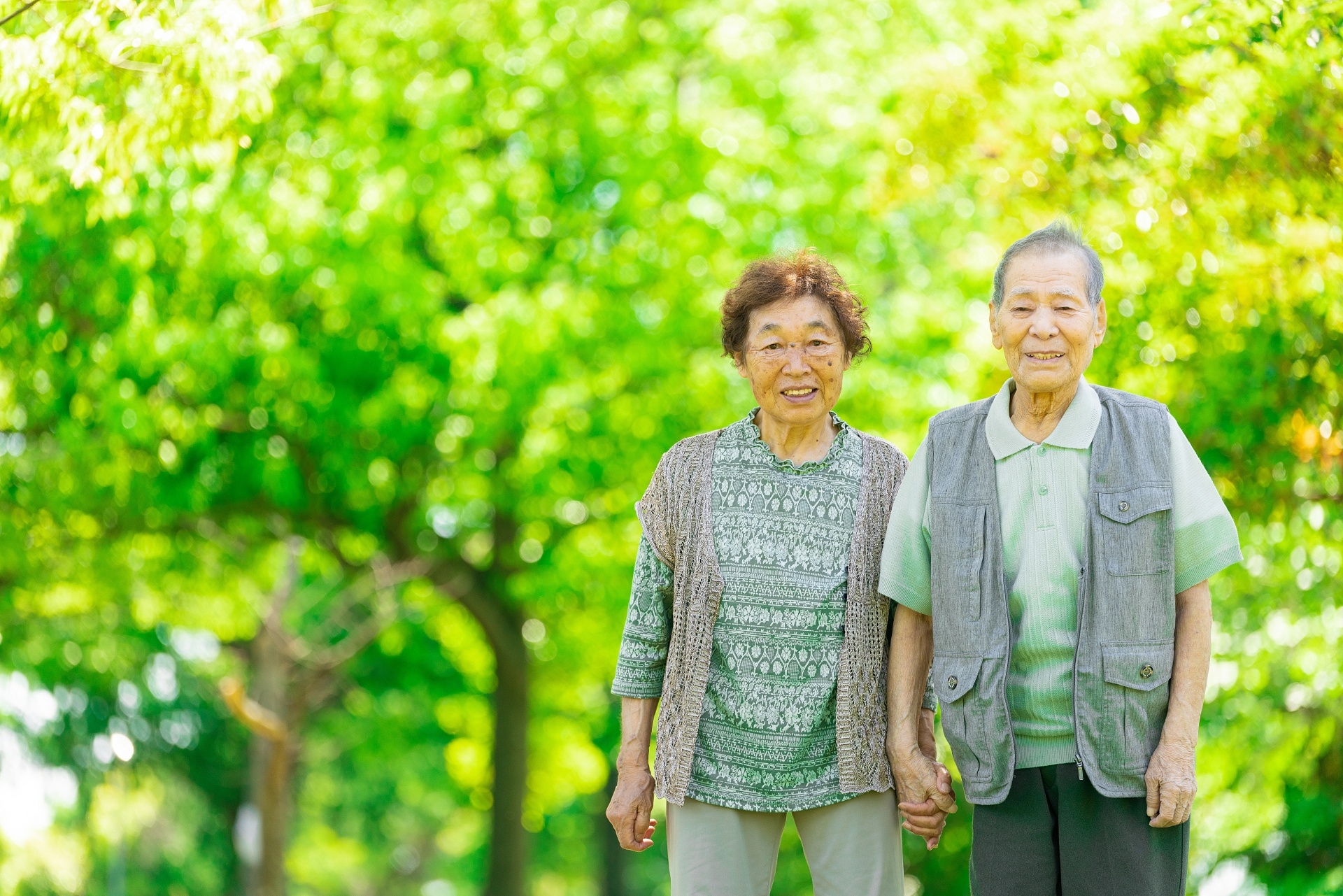 緑の木々を背景にこちらに微笑みかけている老夫婦。